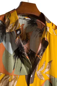Detailed view of yellow tropical leaf print on men's short sleeve Hawaiian shirt lapel