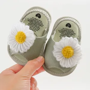 Vue détaillée de sandales vertes pour bébé avec un grand ornement de marguerite blanche