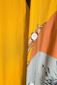 Close-up detail of Hawaiian printed fabric texture and white button on men's shirt