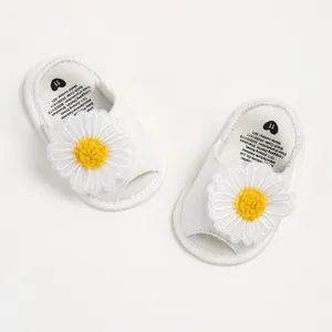 Vue détaillée de dessus de sandales blanches pour bébé avec une grande marguerite décorative