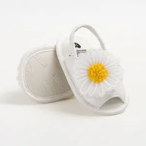 Vue détaillée de sandales blanches pour bébé avec une grande marguerite en tissu.