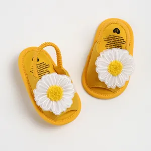 Vue détaillée de la fleur de marguerite et de la semelle des sandales bébé jaunes.