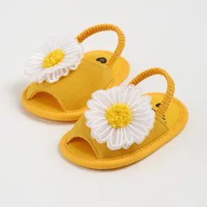 Gros plan détaillé de sandales en textile jaune pour bébé avec marguerites