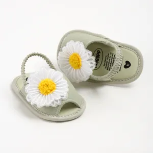 Détail de sandales bébé vert sauge avec un grand ornement de fleur de marguerite