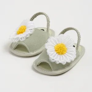 Gros plan de sandales pour bébé vert clair avec décorations marguerites et brides élastiques
