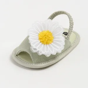 Gros plan d'une sandale pour bébé vert clair avec marguerite blanche et bride souple