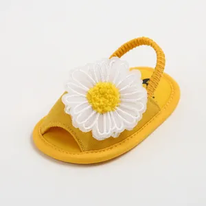 Sandales jaunes pour bébé avec une grande marguerite blanche et bride arrière élastique.
