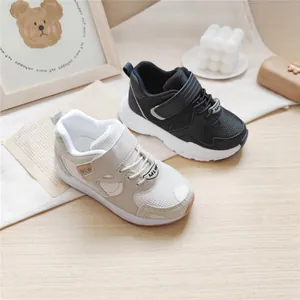 Children's functional sneakers in black and beige displayed with minimalist props.