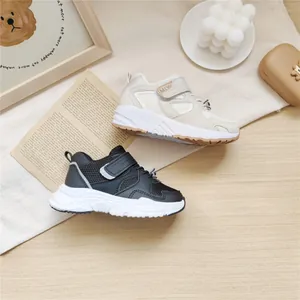 Close-up of black and beige kids' sporty sneakers featuring mesh design and velcro straps