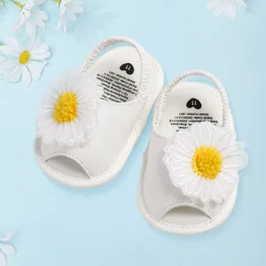 Gros plan de sandales blanches pour bébé avec un charmant détail de grande fleur de marguerite.