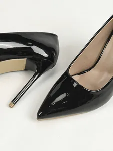 Detalle de zapatos de salón stiletto en charol negro con punta fina y tacones altos