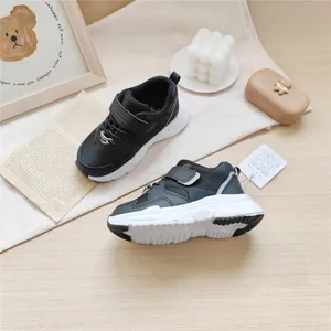 Close-up of black children's functional sneakers with velcro strap on beige mat