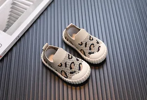 Primo piano di scarpe slip-on in maglia leopardata per bambini su sfondo strutturato.
