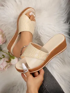 Primer plano de la tira beige con grabado de cocodrilo en sandalias de cuña con plataforma
