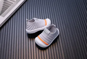 Detailed view of grey and orange knit baby walking shoes on a fluted background