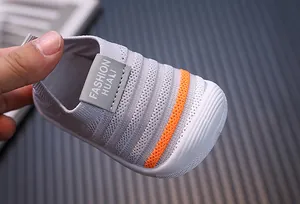 Close-up detail of grey fly-knit baby toddler shoe showing breathable texture and orange stripe