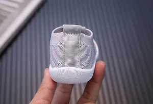 Rear view detail of a light gray breathable fly-knit baby walking shoe with a pull tab