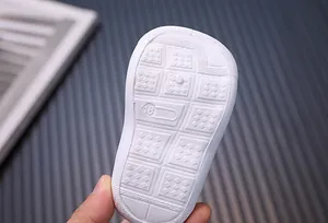 Macro detail of white baby walking shoe sole with non-slip grid pattern and size 16 marking