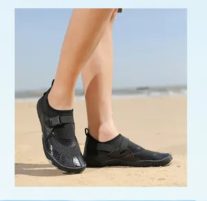 Detailed macro view of black breathable five-toe water shoes being worn on a sandy beach