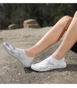 Close-up view of white breathable wading shoes for snorkeling worn on outdoor rocky ground