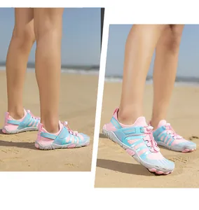 Detail view of pink and blue breathable mesh water shoes worn on a sunny sandy beach