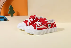 Macro detail view of red toddler canvas shoes featuring durable soft white rubber soles