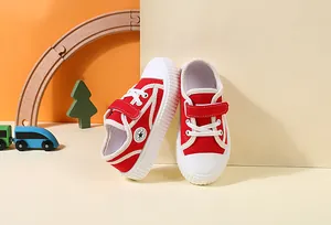 Detailed view of red toddler canvas shoes with white Velcro straps and star logo