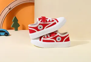 Close-up detail of red toddler canvas sneakers featuring white soft soles and velcro