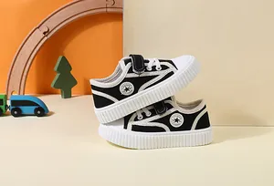 Detailed view of black children's canvas sneakers with velcro strap and star logo