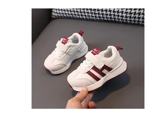 Detail view of white toddler sneakers featuring maroon stripes and non-slip soft rubber soles.