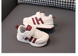 Toddler white leather sneakers with burgundy stripes and a non-slip soft sole.
