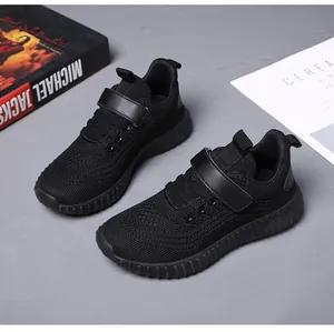 Détail de chaussures de course noires pour enfants avec sangle velcro et maille.