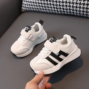 Toddler white leather sneakers with black stripes and adjustable velcro strap for infants