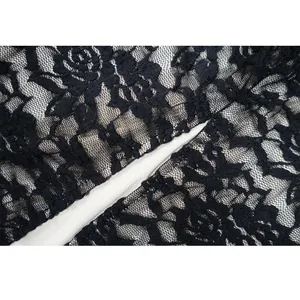 Makrodetail aus schwarzem Blumenspitzenstoff mit weißem Futter an einem sexy Abendkleid.