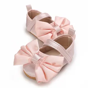 Primer plano de zapatos de princesa rosas para bebé con lazo grande de satén y suela blanda
