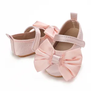 Detalle de zapatos de princesa rosa satinado para bebé con lazo grande