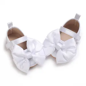Primer plano de zapatos de princesa para bebé blancos con un gran lazo de satén suave