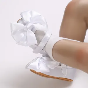 Primer plano de zapatos blancos para bebé niña con un lazo grande y suela blanda
