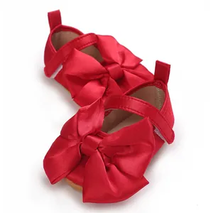 Vista detallada de zapatos de princesa rojos para bebé con un lazo grande de satén
