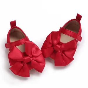 Vista detallada de los zapatos de princesa rojos para bebé con grandes lazos de satén y suela.