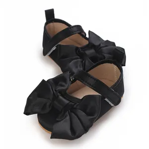 Detalle de zapatos de princesa para bebé negros con un lazo grande de satén