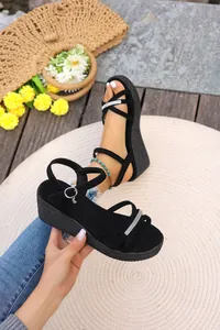 Dettaglio ravvicinato di eleganti sandali platform neri con cinturini in strass.