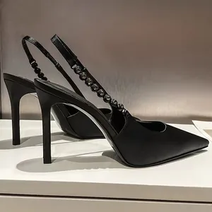 Detailed side view of black pointed-toe slingback heels with elegant rhinestone chain.
