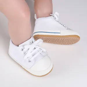 Detalle de los zapatos de lona blanca para bebés con suela de goma antideslizante