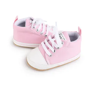 Vista detallada de zapatos de lona rosa para bebés con cordones y puntera blanca
