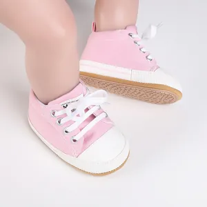 Primer plano de zapatos de lona rosa para bebés con cordones blancos y suela suave.