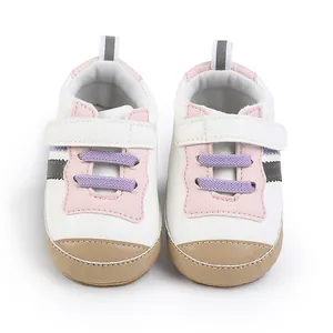 Primo piano di scarpe bianche per primi passi neonato con dettagli rosa e viola
