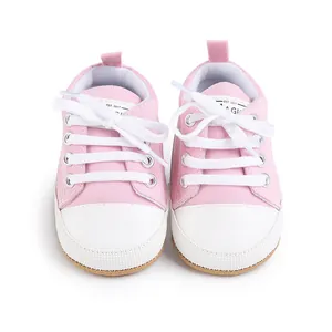 Vista superior de zapatos de lona rosa para bebé con cordones blancos y puntera