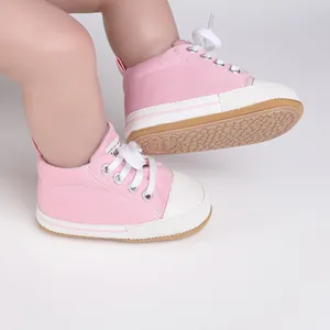 Close-up view of pink canvas baby walking shoes with white laces and anti-slip sole