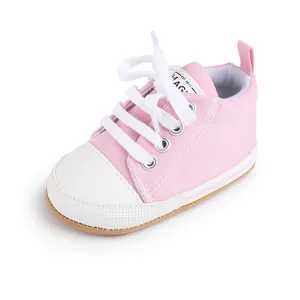 Vista detallada de una zapatilla de lona rosa para bebé con cordones blancos y suela suave